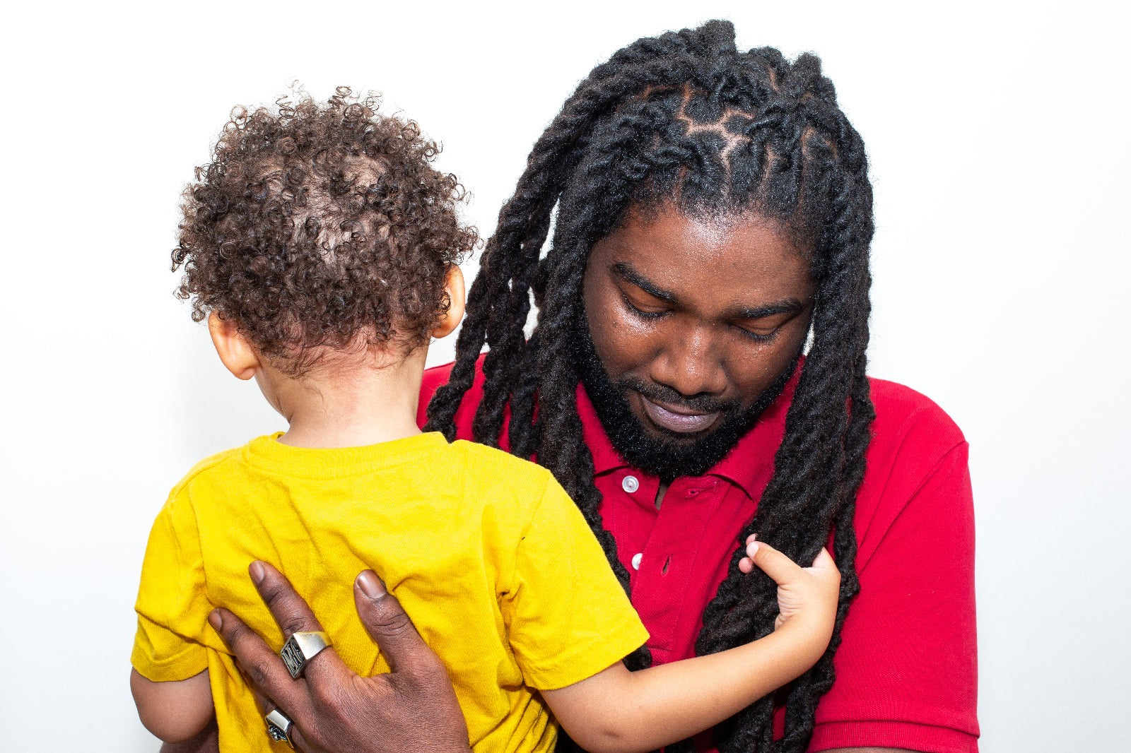 Homme coiffé de locks naturelles avec un enfant métisse dans les bras